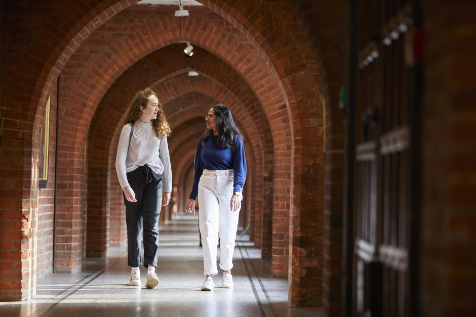 student walking under brick arches in a university