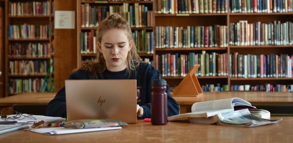 student working on a laptop in a library
