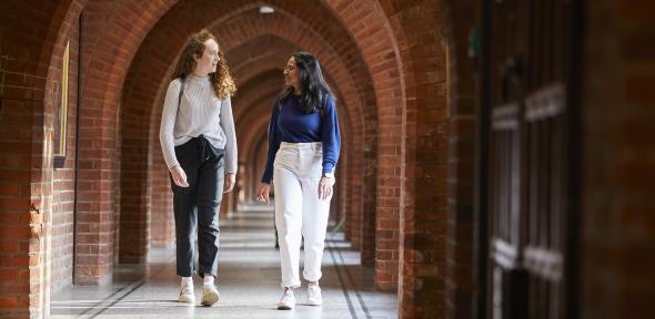student walking under brick arches in a university